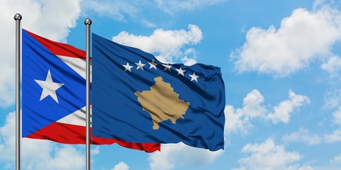 Puerto Rico and Kosovo flag waving in the wind against white cloudy blue sky together. Diplomacy...