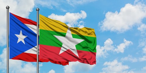 Puerto Rico and Myanmar flag waving in the wind against white cloudy blue sky together. Diplomacy...