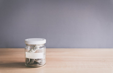 Coin in a glass jar with empty label for text on for wooden desk, Saving money concept