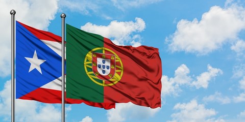 Puerto Rico and Portugal flag waving in the wind against white cloudy blue sky together. Diplomacy concept, international relations.