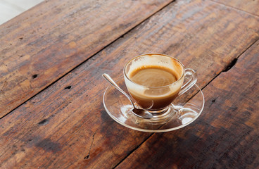 a cup of hot coffee in a glass coffee cup on old wood table 