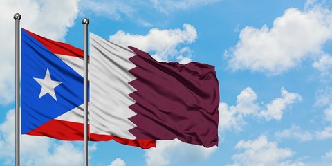 Puerto Rico and Qatar flag waving in the wind against white cloudy blue sky together. Diplomacy...