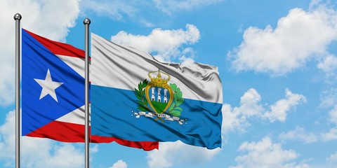 Puerto Rico and San Marino flag waving in the wind against white cloudy blue sky together....