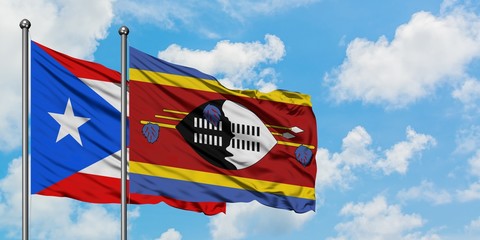 Puerto Rico and Swaziland flag waving in the wind against white cloudy blue sky together. Diplomacy...