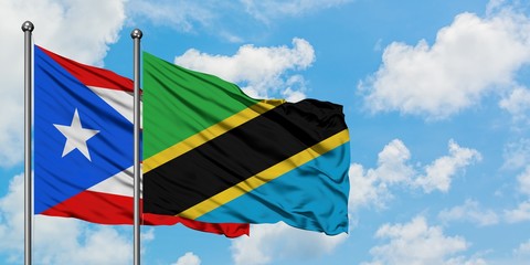 Puerto Rico and Tanzania flag waving in the wind against white cloudy blue sky together. Diplomacy...