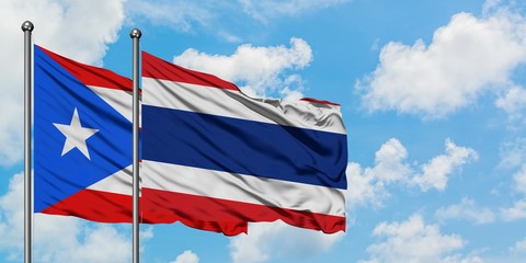 Puerto Rico and Thailand flag waving in the wind against white cloudy blue sky together. Diplomacy concept, international relations.