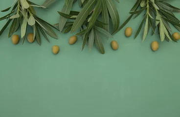 Fototapeten Flat lay Green Olives with olive branch with leaves on green background. Healthy food. Mediterranean diet. Poster, pattern, food background. With copy space for text or image. Top view. © Irina Tarzian