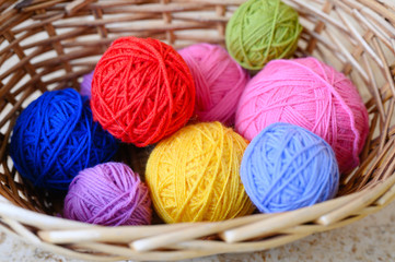 wicker basket with multicolored bright balls of wool yarn for knitting
