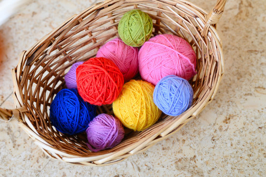 wicker basket with multicolored bright balls of wool yarn for knitting