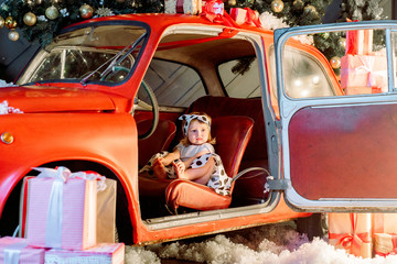 Cute baby blonde, fashionable dress in peas pin-up, red retro car, Christmas lights, New Year card..Christmas happy holiday concept.