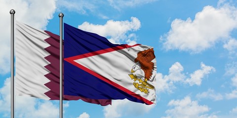 Qatar and American Samoa flag waving in the wind against white cloudy blue sky together. Diplomacy...