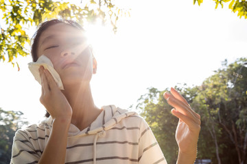 Asian child girl wiping sweat on her face with tissue paper suffer from sunburn very hot in summer...