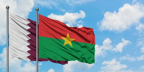 Qatar and Burkina Faso flag waving in the wind against white cloudy blue sky together. Diplomacy...