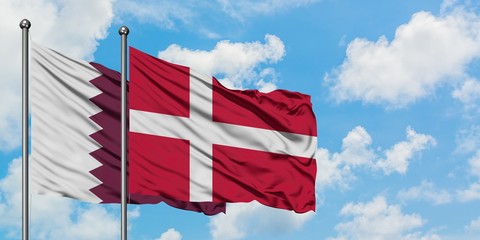 Qatar and Denmark flag waving in the wind against white cloudy blue sky together. Diplomacy concept, international relations.