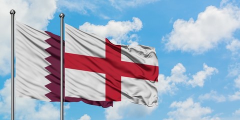 Qatar and England flag waving in the wind against white cloudy blue sky together. Diplomacy...