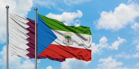 Qatar and Equatorial Guinea flag waving in the wind against white cloudy blue sky together....