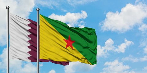 Qatar and French Guiana flag waving in the wind against white cloudy blue sky together. Diplomacy concept, international relations.
