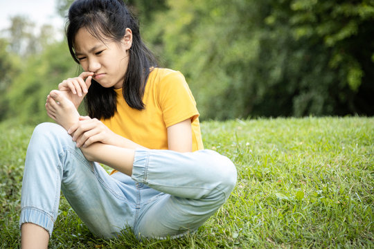 Unhappy Asian Female Teen Is Sniffing Her Feet Smell,hold Her Foot In Her Hand,stink Legs,unpleasant Smell,child Girl With Bad Smell,accumulated Dirt,emotion Facial Expression,foot Skin Care Problem