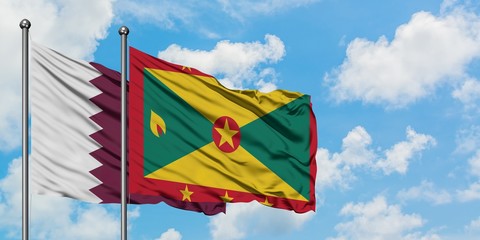 Qatar and Grenada flag waving in the wind against white cloudy blue sky together. Diplomacy...