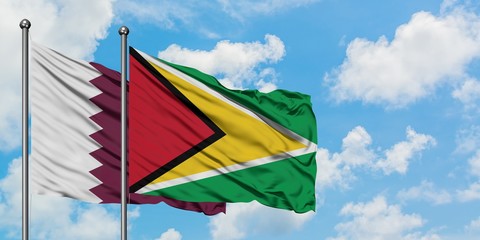Qatar and Guyana flag waving in the wind against white cloudy blue sky together. Diplomacy concept, international relations.