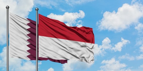 Qatar and Indonesia flag waving in the wind against white cloudy blue sky together. Diplomacy...