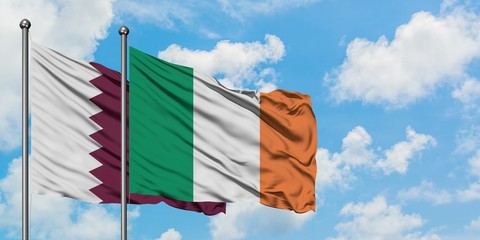 Qatar and Ireland flag waving in the wind against white cloudy blue sky together. Diplomacy...