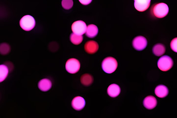 blurred night pink glowing lights on black background. new year and christmas concept