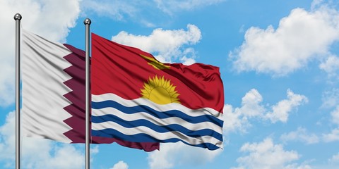 Qatar and Kiribati flag waving in the wind against white cloudy blue sky together. Diplomacy...