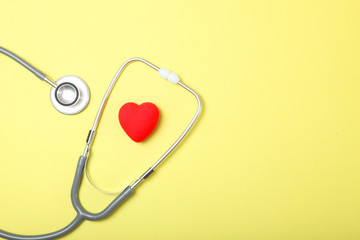 Stethoscope and heart on wooden color background. Health, medicine