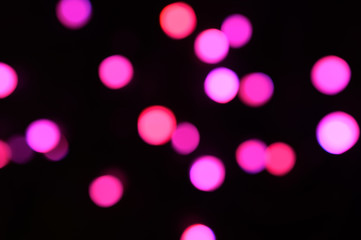 blurred night pink glowing lights on black background. new year and christmas concept