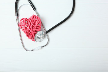 Stethoscope and heart on wooden color background. Health, medicine