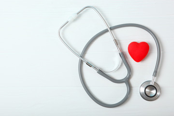 Stethoscope and heart on wooden color background. Health, medicine