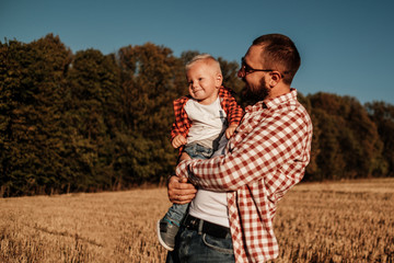 Happy Dad with His Little Son Enjoying Summer Weekend Outside the City in the Field at Sunny Day Sunset