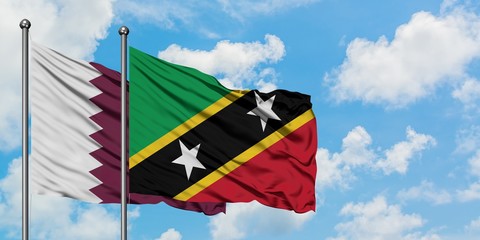Qatar and Saint Kitts And Nevis flag waving in the wind against white cloudy blue sky together. Diplomacy concept, international relations.
