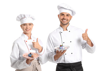 Young confectioners with tasty desserts showing thumb-up gesture on white background