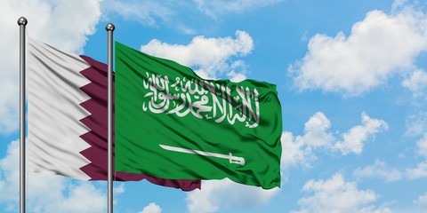 Qatar and Saudi Arabia flag waving in the wind against white cloudy blue sky together. Diplomacy concept, international relations.