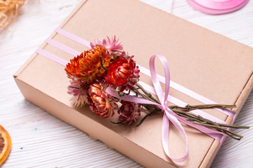 Obraz na płótnie Canvas Cardboard gift box decorated with dried flowers on wooden background