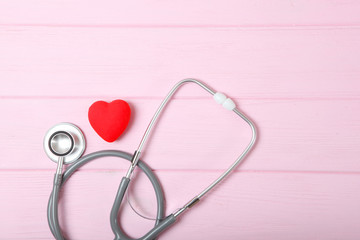 Stethoscope and heart on wooden color background. Health, medicine