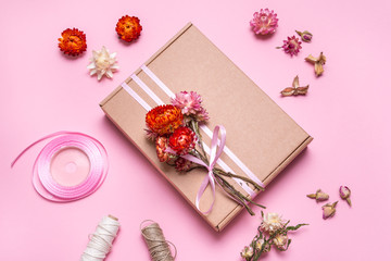 Cardboard gift box decorated with dried flowers on pink background