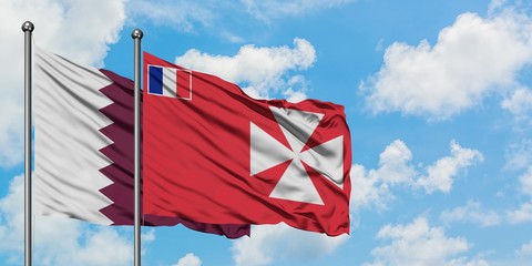 Qatar and Wallis And Futuna flag waving in the wind against white cloudy blue sky together....