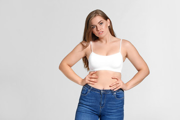 Young body positive woman on grey background