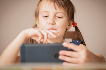 Portrait of serious preschooler child girl holding mobile phone and learning distance outdoors. Study always  and everywhere