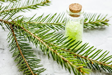 cosmetic spruce salt in bottles with fur branches on white table background