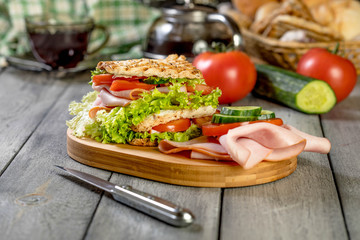 Sandwich with ham, cucumber, tomato and lettuce.