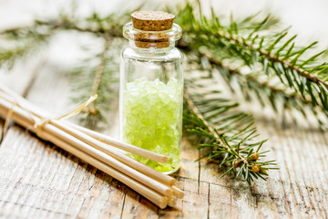Bottles of sea salt and fir branches for aromatherapy and spa on wooden table background