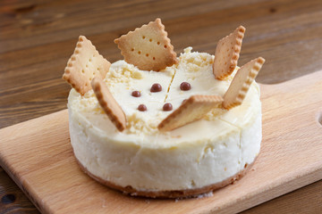 A whole of classic New York cheesecake decorated with square cookies on plate, on wooden table in coffee pastry shop. Cake sweet dessert for holiday, birthday party. Cheesecake for the celebration clo