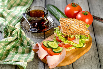 Sandwich with ham, cucumber, tomato and lettuce.