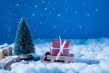 Photo of small wooden toy sledge coming to santa claus place workshop in iceland loaded big red giftbox newyear snowy evening miracle magic concept