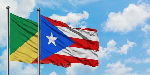 Republic Of The Congo and Puerto Rico flag waving in the wind against white cloudy blue sky...
