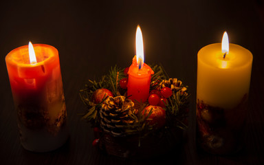 Three burning Christmas candles on a dark background.